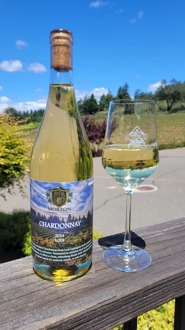 2024 Chardonnay bottle and a poured glass on the tasting room balcony with vineyard views at Morton Family Cellars in Apple Hill, Camino CA