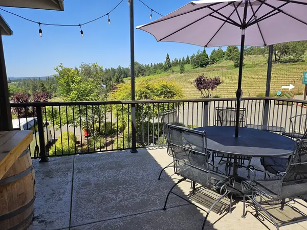 Patio balcony at Morton Family Cellars with bistro seating, umbrellas, and string lights overlooking Biama Vineyard and the Sierra Foothills in Apple Hill, Camino CA